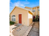 Charming yellow home with a red front door and well-maintained landscaping at 624 Australian Way, Davenport, FL 33897