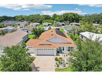 Well maintained house with lush landscaping, 2 car garage, and solar panels on the roof at 703 Royal Palm Ave, Lady Lake, FL 32159