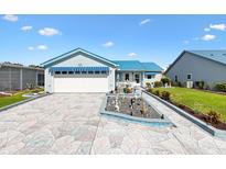Charming single-story home with blue awnings, an attached garage, and a beautifully landscaped front yard at 714 Prado Dr, The Villages, FL 32159