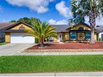 Charming one-story home featuring a well-manicured lawn and vibrant landscaping with beautiful palm trees at 728 Silversmith Cir, Lake Mary, FL 32746
