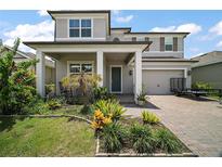 Charming two-story home featuring a well-manicured lawn, covered porch, and attached two-car garage at 9153 Carmela Ave, Davenport, FL 33897