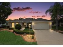 Charming home featuring a well-manicured lawn, lush landscaping, and a two-car garage at 953 Mayo Ct, The Villages, FL 32162