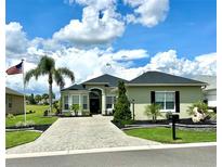 Charming single-story home with a well-manicured lawn, beautiful landscaping, and a paver driveway at 12183 Se 178Th St, Summerfield, FL 34491