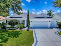 Charming single-story home featuring a well-manicured lawn, a three-car garage, and classic architectural details at 1419 Arbor Trl, The Villages, FL 32162