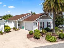 Charming single-story home with a well-manicured lawn and a driveway leading to an attached garage at 1762 Meadowlark Ave, The Villages, FL 32162
