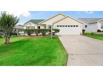 Charming single-story home featuring a well-manicured lawn, two-car garage, and appealing landscaping at 17860 Se 89Th Natchez Ave, The Villages, FL 32162