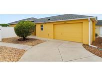 Home with a well manicured lawn, beautiful shrub, and a two car garage at 2101 Southern Star Way, The Villages, FL 32162
