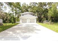 Two-story home with a two-car garage and a long driveway, surrounded by mature trees at 2114 Waitman Ave Waitman, Leesburg, FL 34748