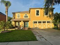 Inviting two-story home with a well-manicured lawn, palm trees, and a stylish garage door design at 2122 Waseca Ln, Leesburg, FL 34748