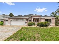 Charming single-story home with a three-car garage and well-manicured lawn and landscaped bushes at 2881 Manor Downs, The Villages, FL 32162