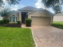 Charming single-story home featuring a brick driveway, well-manicured lawn, and a two-car garage at 3621 Kingswood Ct, Clermont, FL 34711