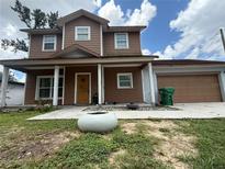 Charming two-story home with a covered front porch and attached two-car garage with a brown door at 402 E Maple St, Winter Garden, FL 34787