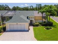 Well-maintained home featuring lush landscaping, palm trees, brick driveway, and a screened-in porch perfect for relaxation at 425 Glen Arbor Ln, Leesburg, FL 34748