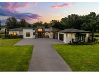 Striking modern home with lush landscaping, a paved driveway, and a welcoming entrance at sunset at 6031 Dora Dr, Mount Dora, FL 32757