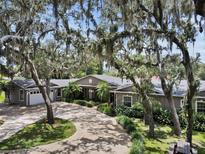 Inviting home with lush landscaping, mature trees and a circular driveway leading to an attached three-car garage at 81 N Carol Ave, Mascotte, FL 34753