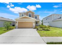 Charming two-story home featuring a tan exterior, landscaped yard, and a spacious two-car garage at 853 Blue Creek Dr, Haines City, FL 33844