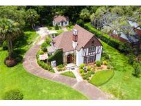 Elegant Tudor-style home featuring beautiful landscaping, a stone entrance, and a winding driveway at 9233 Silver Lake Dr, Leesburg, FL 34788