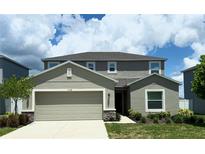 Two-story home featuring neutral paint, two car garage, manicured landscaping, and a concrete driveway at 1138 Calico Pointe Cir, Groveland, FL 34736