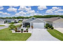 Charming home featuring an attached garage, manicured lawn, and decorative white picket fence surrounding a landscaped garden at 1478 Erika Pl, The Villages, FL 32163