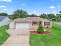 Charming single-story home featuring a two-car garage, well-manicured lawn and colorful landscaping at 1948 Harston Trl, The Villages, FL 32162