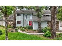 Charming two-story home with gray siding, stone accents, a landscaped yard, and a vibrant red front door at 2108 Dogwood Cir, Mount Dora, FL 32757