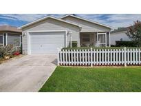 Charming home featuring a one-car garage, screened porch, and a classic white picket fence at 2311 Pine Ridge St, The Villages, FL 32162