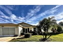 Charming home with manicured lawn, vibrant landscaping, and inviting front entrance at 327 Bentwood Dr, Leesburg, FL 34748
