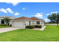 Charming single-story home with a well-manicured lawn and attached garage, near a scenic lake at 5715 Illumination Ln, Leesburg, FL 34748