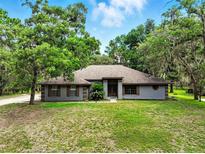 Charming single-story home with mature trees, a well-maintained lawn, and neutral colored exterior at 1053 Cavern Dr, Apopka, FL 32712