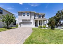 Charming two-story home with a well-manicured lawn and a paver driveway leading to a two-car garage at 1131 Dora Parc Ln, Mount Dora, FL 32757
