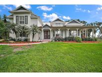 Stunning two-story home featuring a large front yard, brick path, and inviting wrap-around porch at 15104 County Road 48, Astatula, FL 34705