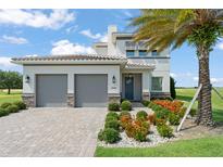 Beautiful two-story home featuring a two-car garage, lovely landscaping, and a healthy palm tree at 16030 Vetta Dr, Bella Collina, FL 34756