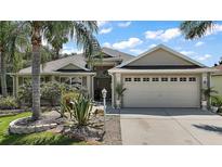 Charming single-story home featuring a well-manicured lawn, mature landscaping, and a two-car garage on a sunny day at 2265 Hackney Way, The Villages, FL 32162