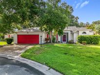 Charming single-story home boasts a red garage door and well-maintained landscaping at 26338 Glen Eagle, Leesburg, FL 34748