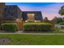 Charming home featuring a unique roof design, lush landscaping, and a welcoming fenced-in front yard at 2920 Poplar Ave, Leesburg, FL 34748