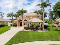 Beautiful two-story stucco home features manicured lawn, decorative shrubs, and mature palm trees in a tropical landscape at 4548 Barrister Dr, Clermont, FL 34711