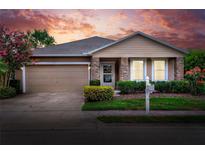 Charming single-story home featuring stone accents, landscaped front yard, and two-car garage at sunset at 6906 Glenbrook Dr, Lakeland, FL 33811
