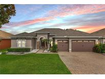 Charming single-story home featuring a well-manicured lawn, three-car garage, and elegant stone accents at 9413 Ivywood St, Clermont, FL 34711