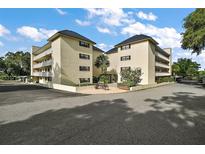 A low angle shot of condo with white brick, black roofs, manicured landscape, benches, and ample parking at 101 N Grandview St # 103, Mount Dora, FL 32757