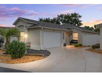 Charming single-story home featuring a well-manicured lawn, beautiful landscaping, and a two-car garage at 1065 Berg Ct, The Villages, FL 32162