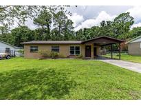 Charming single-story home with well-maintained lawn, covered parking, and inviting curb appeal at 1415 Braebury Dr, Leesburg, FL 34748