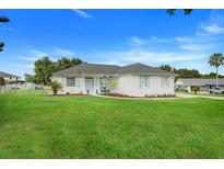 Charming single-story home with a well-manicured lawn, and light blue shutters and front door at 15629 Catherine Cir, Groveland, FL 34736