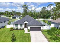 Charming single-story home with a well-manicured lawn, gray roof, white exterior, and a two-car garage at 1620 6Th Ave, Deland, FL 32724