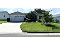 Charming single-story home with well-maintained lawn, mature trees, and a two-car garage at 17483 Se 74Th Netherclift Ter, The Villages, FL 32162