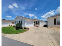 Charming single-story home featuring a well-maintained lawn and a spacious driveway leading to an attached garage at 17695 Se 84Th Peyton Ct, The Villages, FL 32162
