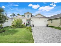 Charming single-story home featuring manicured lawn, brick driveway, and a welcoming front entrance at 1990 Wallingford Loop, Mount Dora, FL 32757
