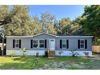 Charming single-story home with gray siding, black shutters, and a well-maintained lawn at 207 Skyline Dr, Lady Lake, FL 32159