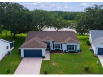 Charming single-story home features a brick driveway, well-manicured lawn, and a view of the lake at 24954 Navel Ave, Leesburg, FL 34748