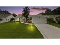 Charming single-story home with a well-manicured lawn, attached two-car garage, and inviting blue front door at 26034 Oakmount Dr, Leesburg, FL 34748