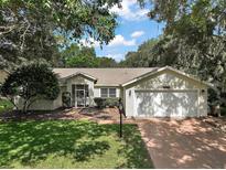 Charming single-story home with lush landscaping, a screened entrance, and a two-car garage at 4300 Leafway Cir, Leesburg, FL 34748